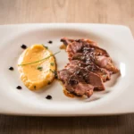 Magret de canard au miel épicé, tranché et servi avec une purée de roquette onctueuse, présentation gastronomique.