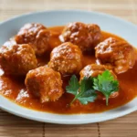 boulettes de viande dans une sauce tomate, servies sur une assiette blanche.