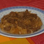 Bœuf aux oignons à la chinoise dans un plat en céramique, nappé de sauce brune.