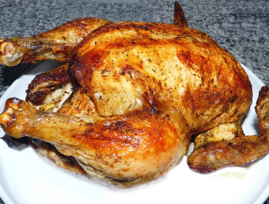 Astuce de cuisson pour la volaille : gros plan sur la peau croustillante et dorée d'un poulet rôti sortant du four.