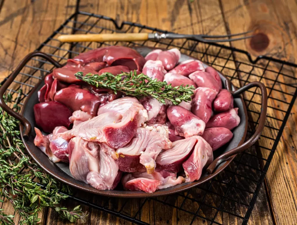 Gros plan sur des abats de poulet crus et frais, nettoyés et prêts pour la cuisson, illustrant la préparation des abats de volaille.
