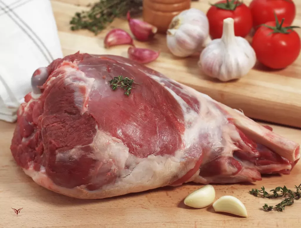 Technique de préparation de l'agneau : piquage d'un gigot d'agneau avec de l'ail et du romarin avant la cuisson au four.