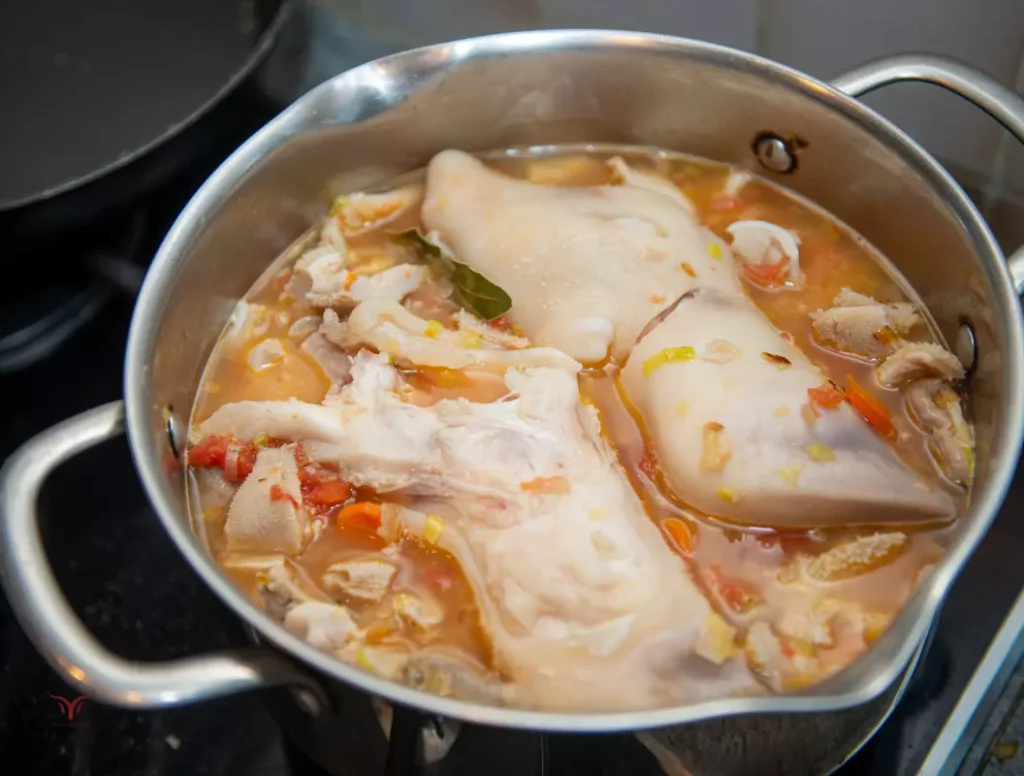 Tripes à la mode de Caen en cours de cuisson dans une cocotte, montrant les tripes, le pied de bœuf et les légumes.