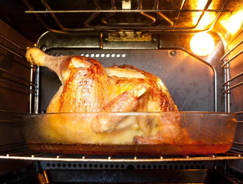 Chapon rôti au four avec jus de cuisson doré dans le plat.