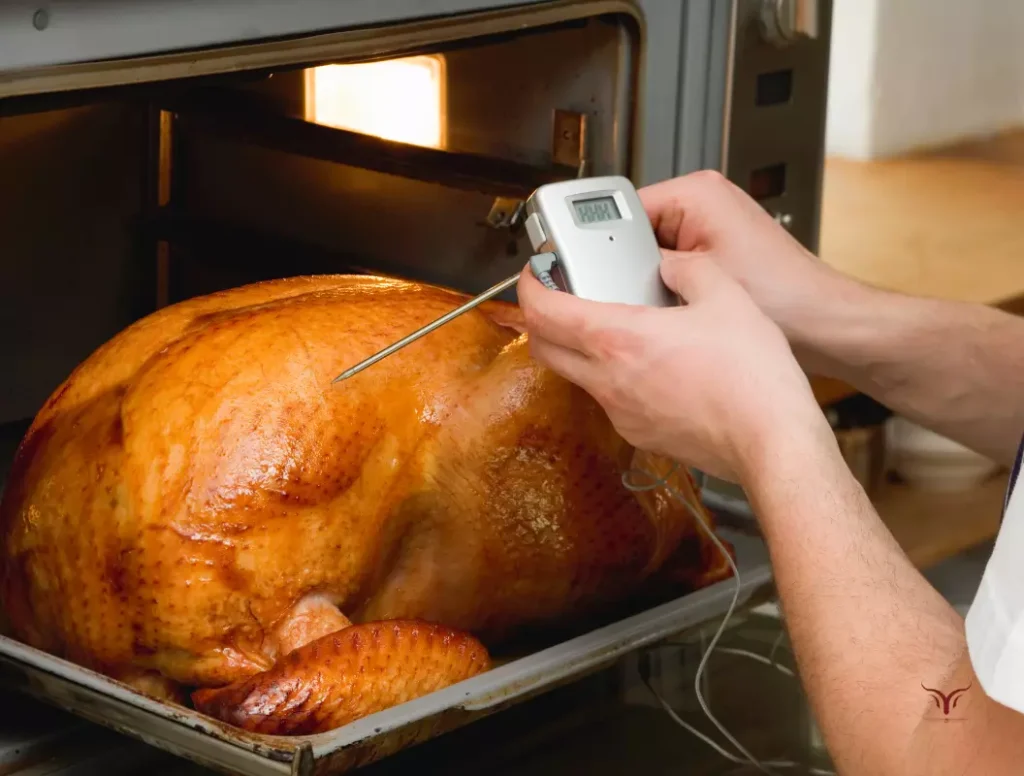 Un thermomètre de cuisson planté dans la cuisse d'une dinde de Noël rôtie indiquant la température parfaite