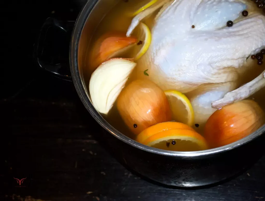 Une dinde crue plongeant dans une grande marmite de saumure liquide aromatisée